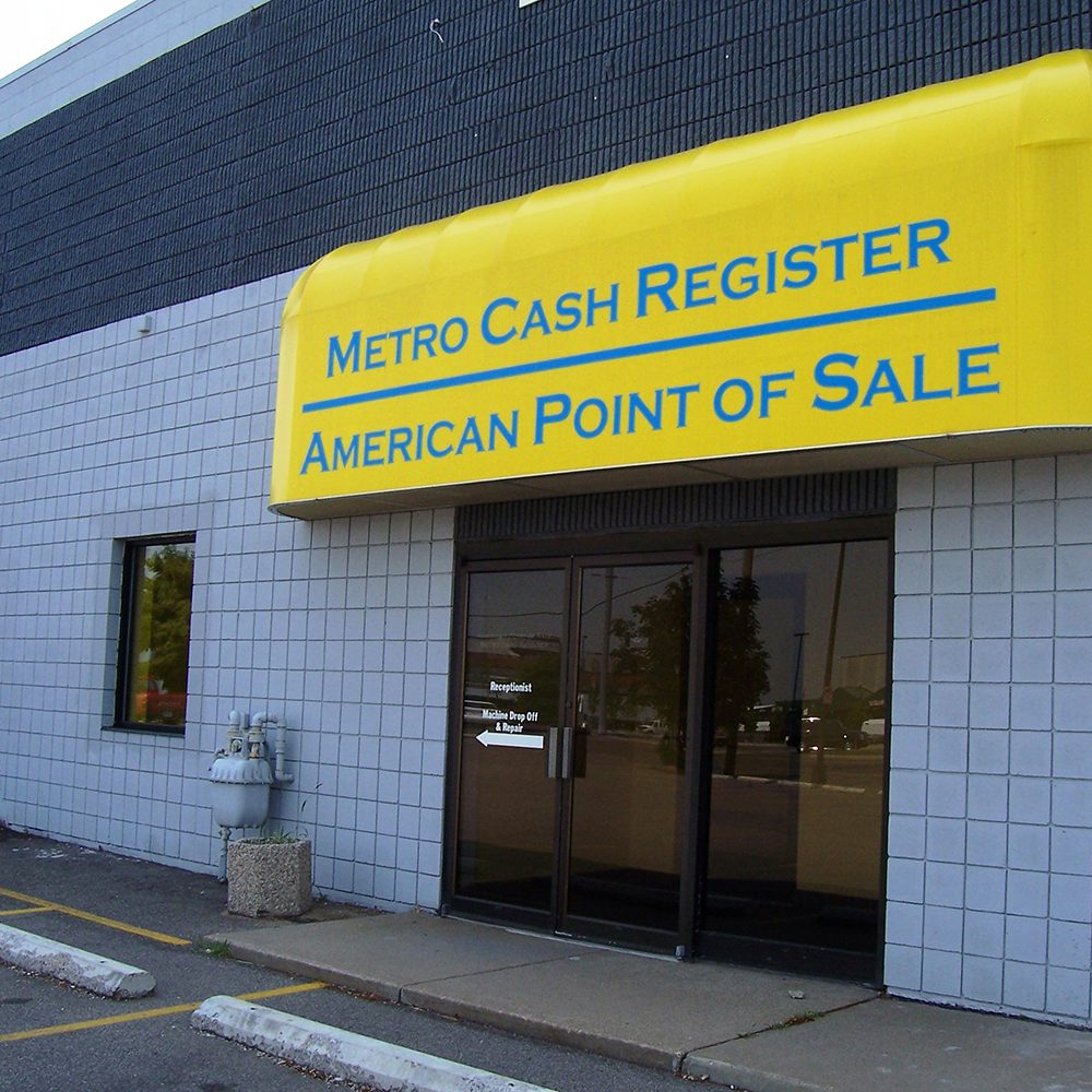 Exterior view of the metro cash register and american point of sale store featuring a yellow awning with visible signage above the entrance.