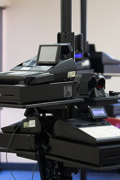A modern black multifunction professional printer in an office setting, equipped with multiple paper trays and digital displays.